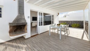 Eine Terrasse im Freien mit Kamin aus Stein, einem Esstisch und Stühlen.
