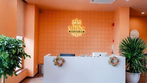 A reception desk with a neon sign reading "MONA MONARCH REST" and a crown symbol. - Mona Hotel (Ho Chi Minh City)