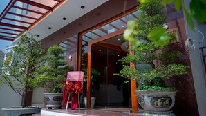 A hotel entrance with a glass door, potted plants, and a sign reading "Grand Momo House". - Mona Hotel (Ho Chi Minh City)