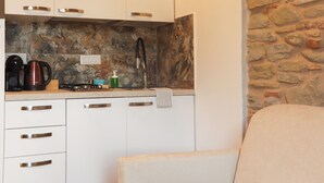 A modern kitchen with white cabinets, a stone backsplash, and a beige sofa in the foreground. - Villa with private pool and spa, walking city x25 (Modigliana)