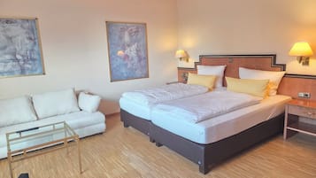 Ein Hotelzimmer mit einem großen Bett, einer Couch, zwei Wandleuchten und abstrakter Kunst an den Wänden.