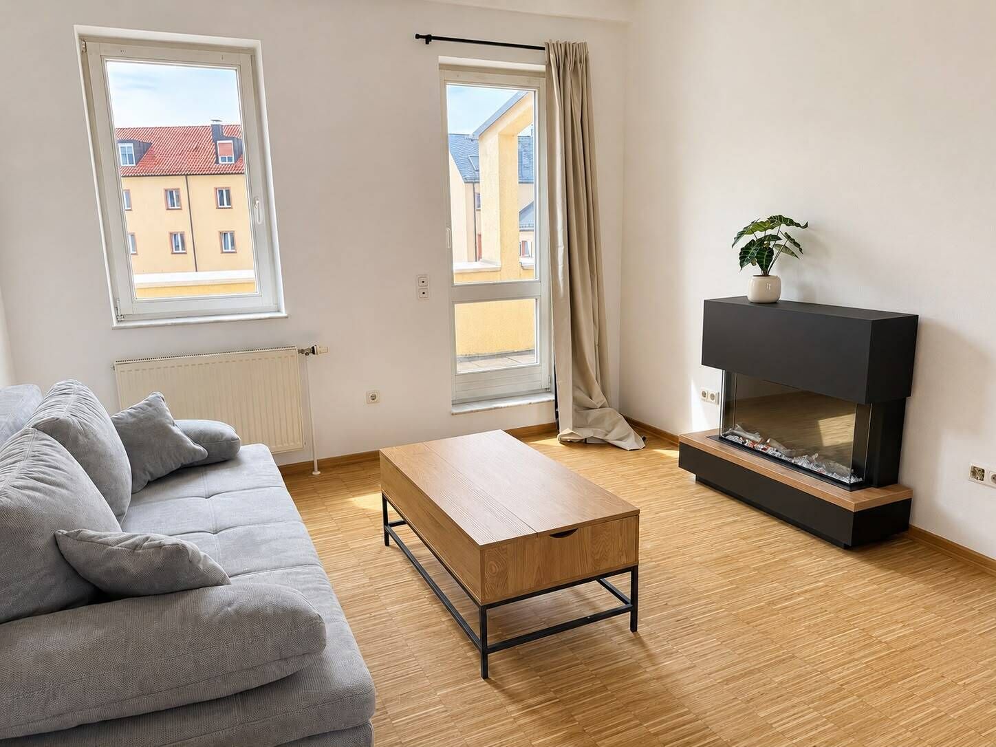 Ett vardagsrum med en soffa, ett soffbord, en tv och en växt.