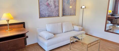 A modern living room with a sofa, a coffee table, a lamp, and two abstract paintings on the wall.