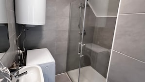 Un baño moderno con cabina de ducha de vidrio, un lavabo y un inodoro.