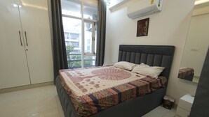 A bedroom with a bed, a wardrobe, a small bedside table, and a window with curtains.