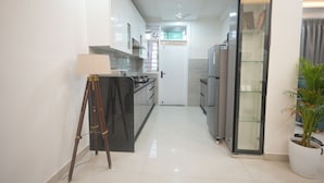 A narrow kitchen with white cabinets, a black countertop, and a tripod.