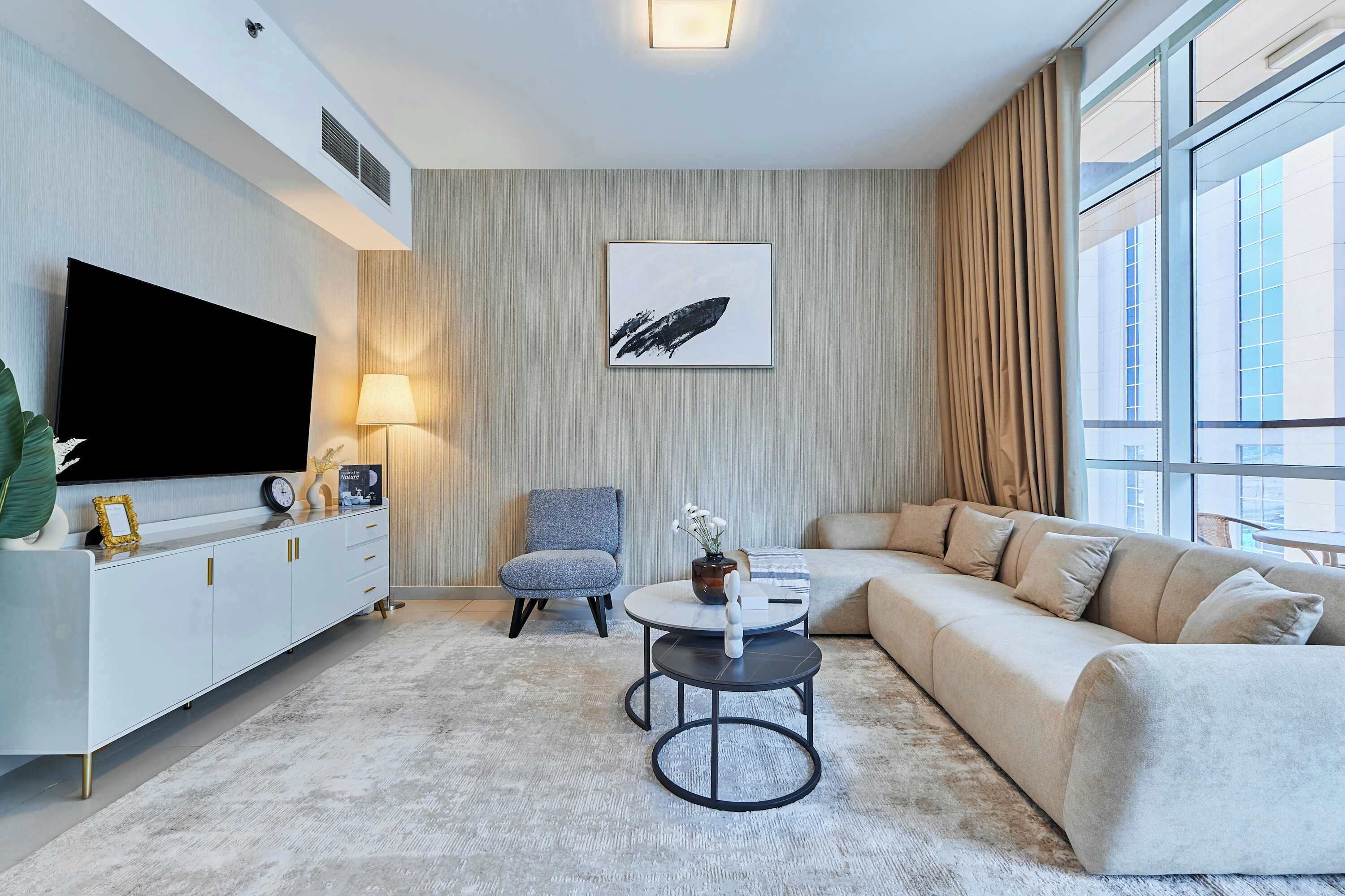 A modern living room with a flat-screen TV, a sofa, a coffee table, and a chair.