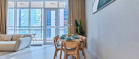 A modern living room with a dining area, large windows, and a view of the cityscape.