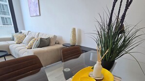 Un espace repas moderne avec une table en verre, une assiette jaune et une plante en pot.