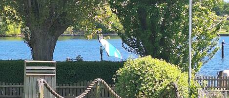 An outdoor seating area with a table and chairs, a flagpole with a flag, and a large tree.