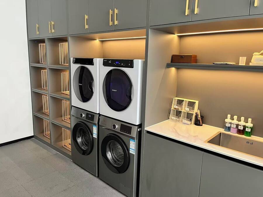 A modern laundry room with two front-loading washing machines and a built-in sink with storage shelves.
