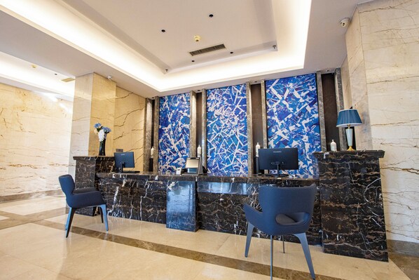 A modern reception area with marble counters, blue chairs, and a large abstract mural. - XIAMENAIR TIANJIN HOTEL (Tianjin)