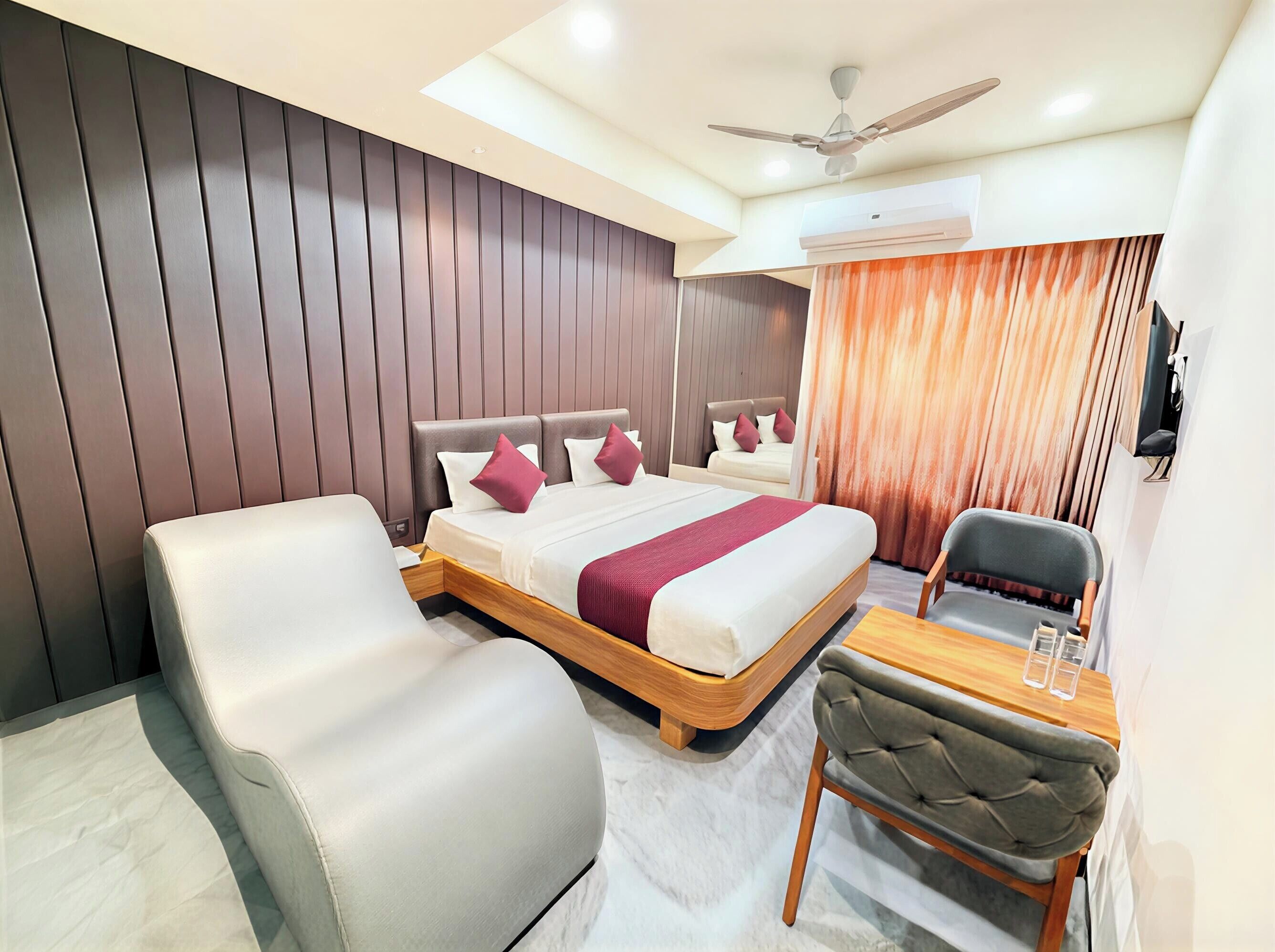 Una habitación de hotel moderna con una cama grande, un escritorio, una silla y un ventilador de techo.