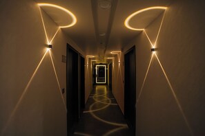 A hallway with modern lighting fixtures creating geometric patterns on the walls and floor. - Hotel The Avanta - Gandhinagar (Gandhinagar)