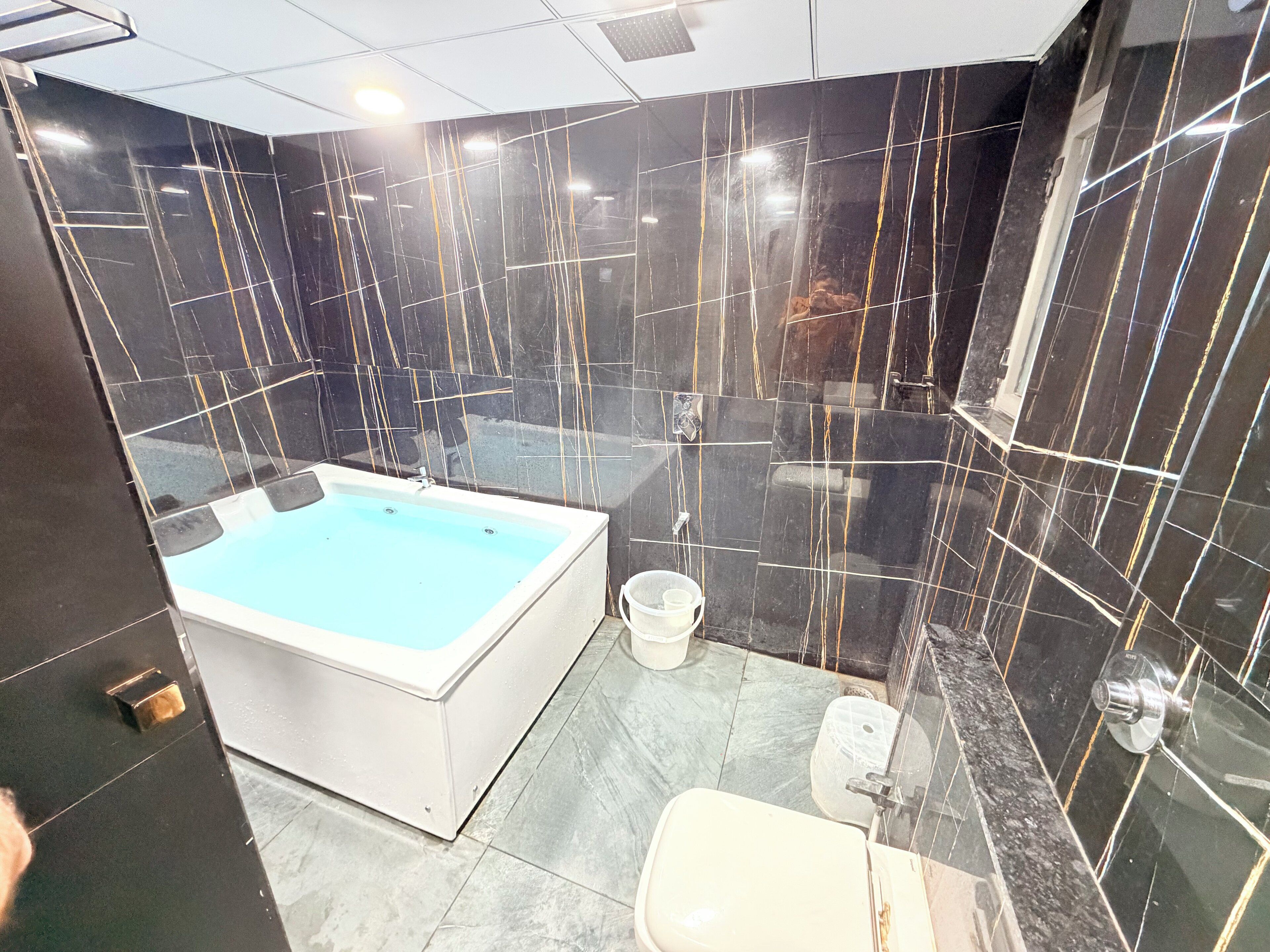 Et moderne badeværelse med et stort badekar, toilet og bruseniche.