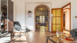 Un soggiorno moderno con un tavolino in vetro, una poltrona comoda e una zona pranzo visibile tramite un arco.