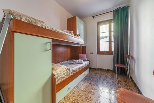 Une chambre de dortoir avec des lits superposés, une chaise et une fenêtre avec des rideaux.