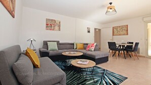 Una sala de estar moderna con un sofá gris, una mesa de centro y un comedor con mesa y sillas.
