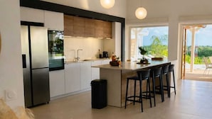 Een moderne keuken met een centraal eiland, witte kastjes en hanglampen.