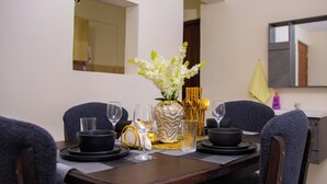 Une table à manger dressée avec de l’assiette, des bols et des verres noirs, un vase décoratif contenant des fleurs blanches et un centre de table orné de motifs dorés.