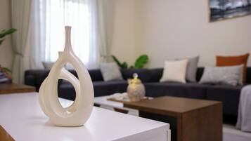 Een moderne woonkamer met een witte vaas op een tafel, een donkere bank met kussens, en een houten salontafel.