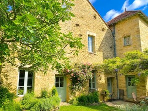 A stone building with a green door, a small garden with pink flowers, and a table with chairs outside. - Billebaude guest room -Breakfast included (Montoillot)