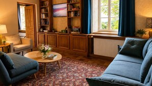 A cozy living room with a sofa, a coffee table, a bookshelf, and a TV. - Biche Blanche guest room - Breakfast included (Montoillot)