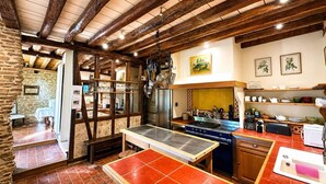 A rustic kitchen with exposed wooden beams, a large stove, and a dining table. - Biche Blanche guest room - Breakfast included (Montoillot)