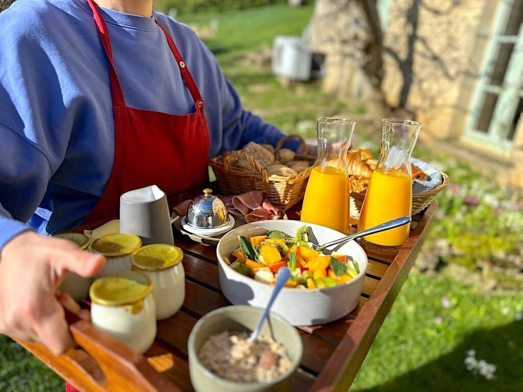 Un plateau de petit-déjeuner avec un bol de salade de fruits, deux verres de jus d’orange et un petit bol de céréales.
