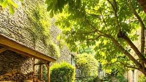 A stone pathway leading to a wooden structure with a stone wall and a pile of firewood. - Le Cocon de la Grange (Montoillot)