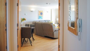 Ein modernes Wohnzimmer mit einer Couch, einem Esstisch mit Stühlen und einem großen Spiegel an der Wand.