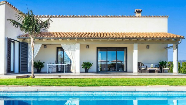 A modern house with a swimming pool, a patio with outdoor furniture, and a well-maintained lawn. - 2 Cortons - Wall (Muro)