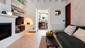 A living room with a fireplace, a green sofa, a wooden coffee table, and a basket of lemons. - Can Miguel (Sineu)