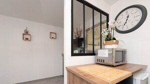 A kitchen with a wooden countertop, a microwave, and a clock on the wall. - Ty Avel Apartment with Shared Pool, Balcony, and Wi-Fi (Quiberon)