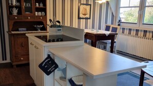 Een keuken met een wit aanrechtblad, houten kastjes en een gestreepte wand.