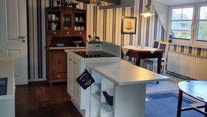 Een keuken met een wit eiland, houten kasten en gestreept behang.
