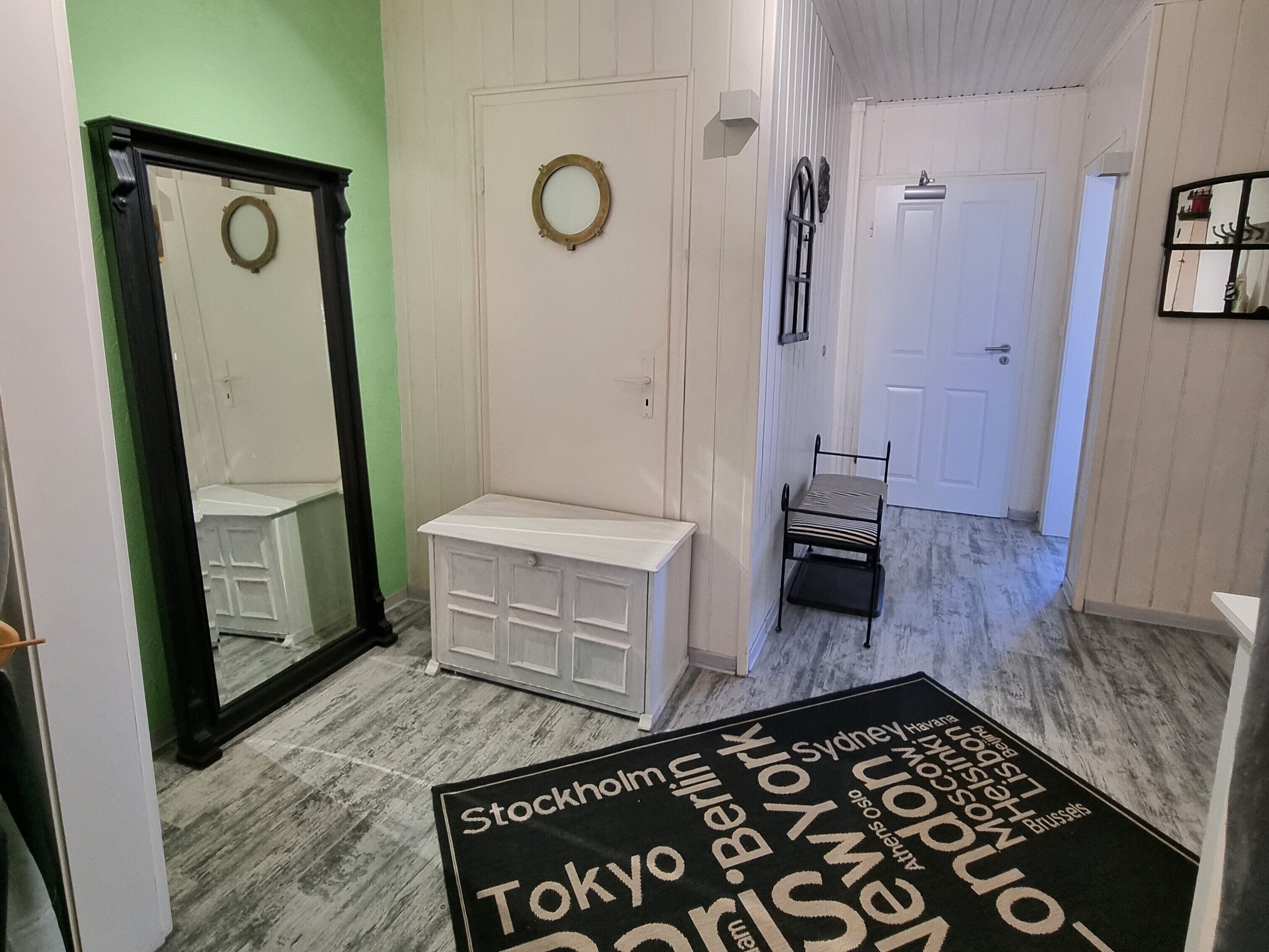 A hallway with a white bench, a mirror, and a door.