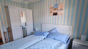 Ein Schlafzimmer mit einem Bett, Nachttischen, einem Kleiderschrank und einer Wand mit Streifenmuster.