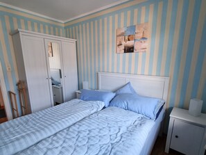 Ein Schlafzimmer mit einem Bett, Nachttischen, einem Kleiderschrank und einer Wand mit Streifenmuster.