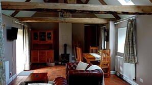 Un loft espacioso con vigas de madera a la vista, un comedor y una zona de estar acogedora con sofás de cuero.