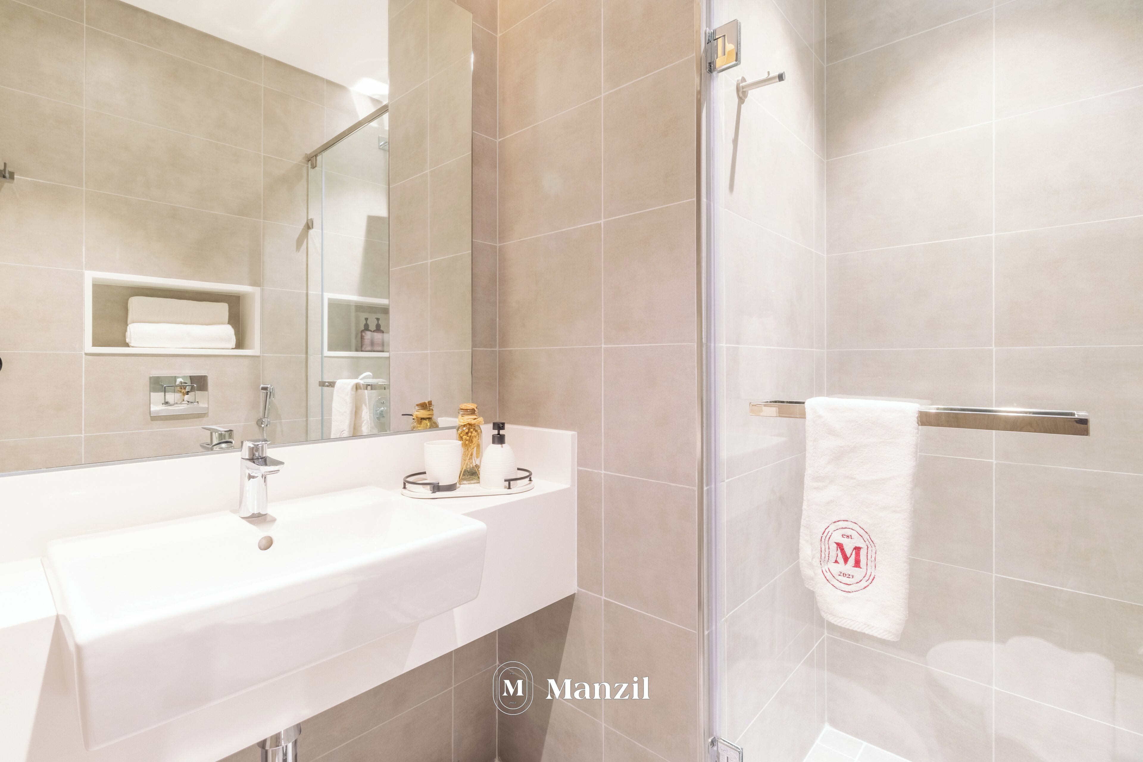 A modern bathroom with a large mirror, a sink, and a glass shower enclosure.