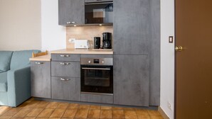A compact kitchen with grey cabinets, a built-in oven, and a coffee maker. - Beautiful apartment with mountain views - sleeps 8 (Orcières)