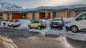 A building with a snow-covered roof and a parking area with several cars. - Beautiful apartment with mountain views - sleeps 8 (Orcières)