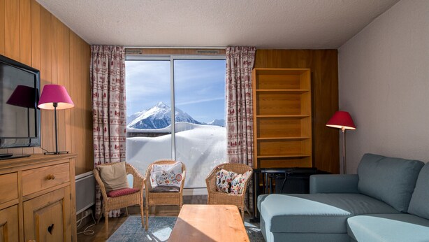 A cozy room with a wooden cabinet, two wicker chairs, a blue sofa, and a wooden table. - Beautiful apartment with mountain views - sleeps 8 (Orcières)