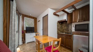 A compact kitchen with wooden cabinets, a microwave, and a refrigerator. - Beautiful apartment with mountain views - sleeps 8 (Orcières)