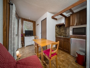 A compact kitchen with wooden cabinets, a microwave, and a refrigerator. - Beautiful apartment with mountain views - sleeps 8 (Orcières)