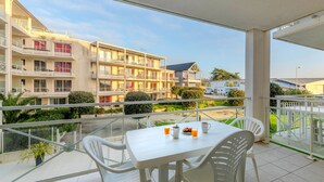 A balcony with a table and chairs, overlooking a building with multiple balconies and a garden. - Bright apartment, balcony, sleeps 4 (Plougonvelin)