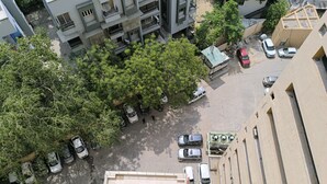 An aerial view of a parking lot with several cars parked, surrounded by buildings and trees. - HOTEL SELFIE INN (Ahmedabad)