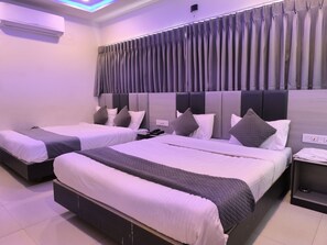 Habitación de hotel con dos camas, un cabecero moderno y una lámpara en el techo.