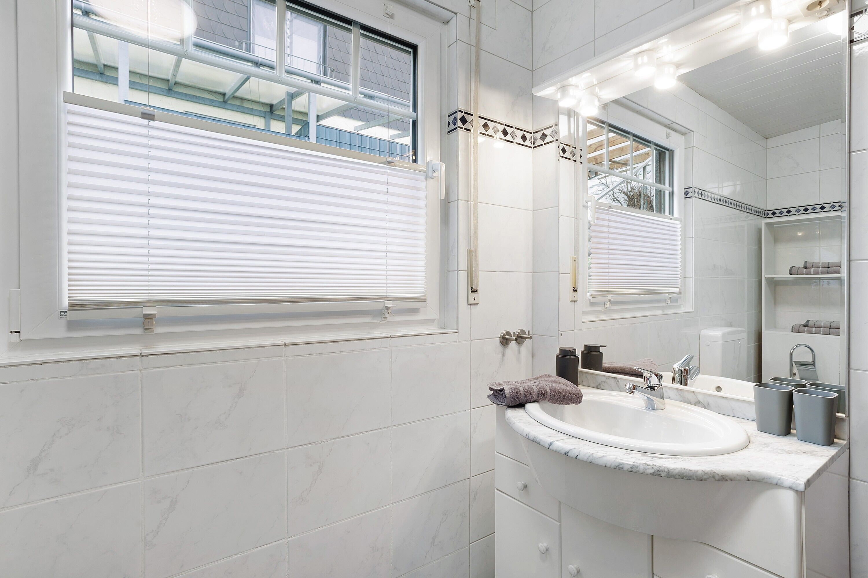 Une salle de bain avec un lavabo blanc, un miroir et un porte-serviettes.